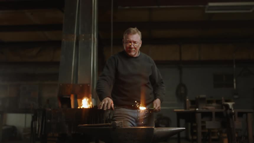A man working on forging some metal on an anvil
