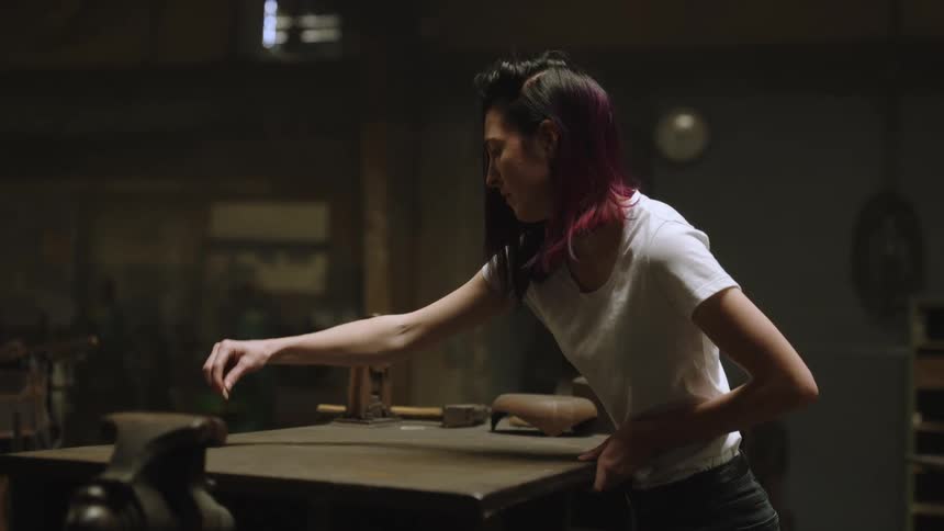 A woman standing at a work bench draws marks and lines using a tailors chalk