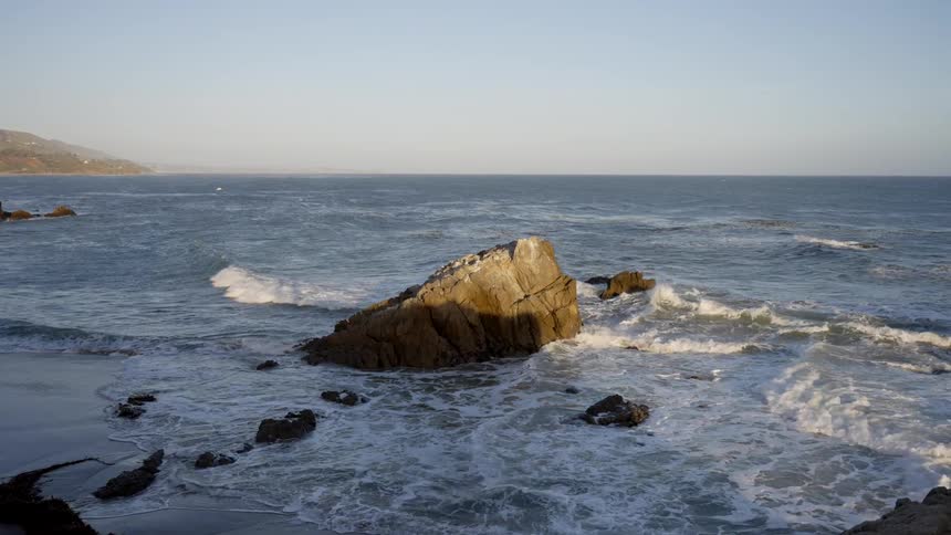 Ocean waves splash against the rocks as they come to shore
