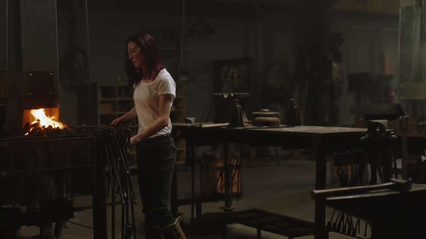 A woman is stirring coal in the oven