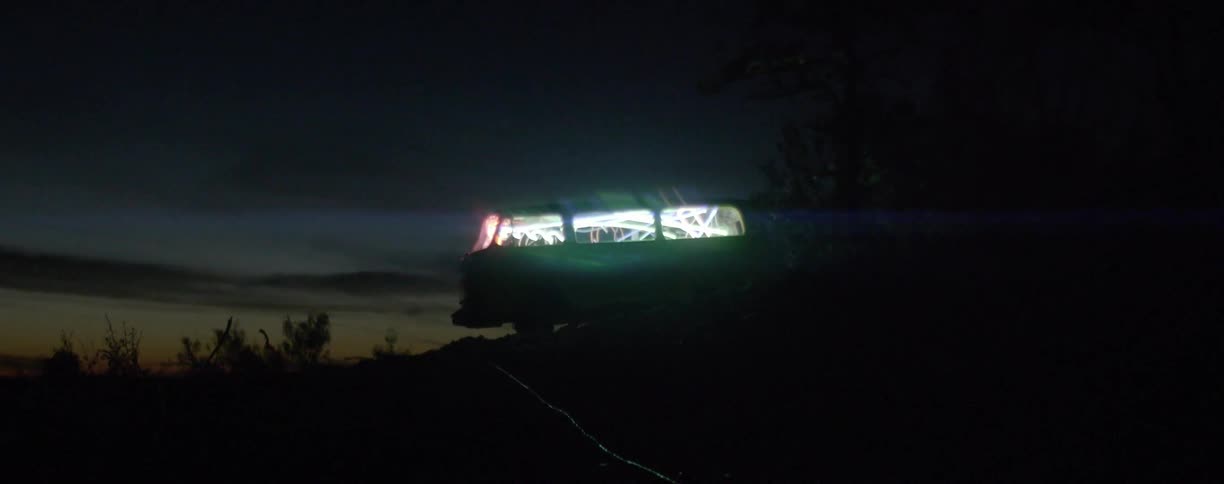 A van on a hill has many lights in it at night