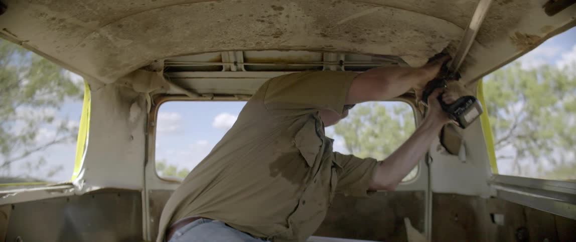 A man is drilling into the roof of a van