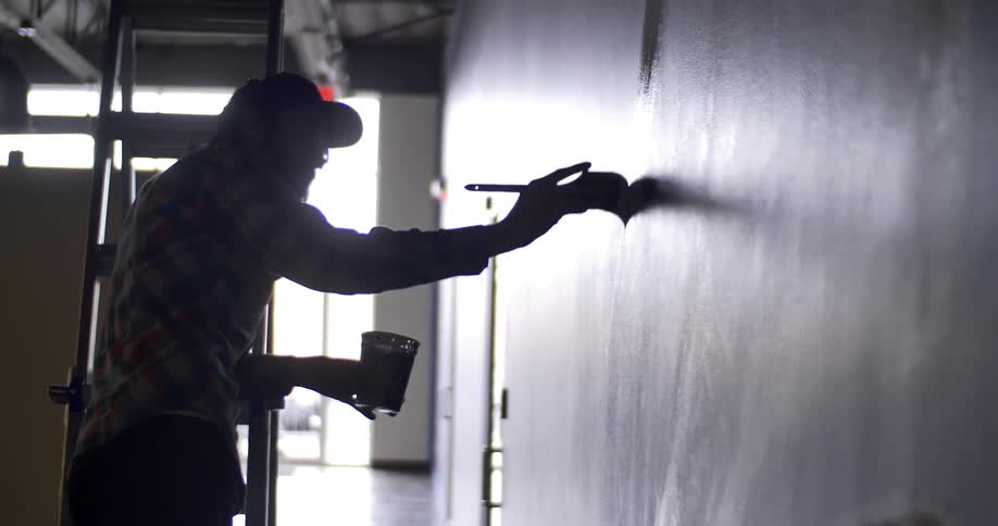 A man is painting with a cup in his hand