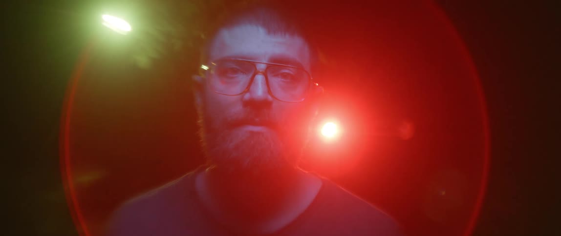A man stands in front of bright flashing spotlights