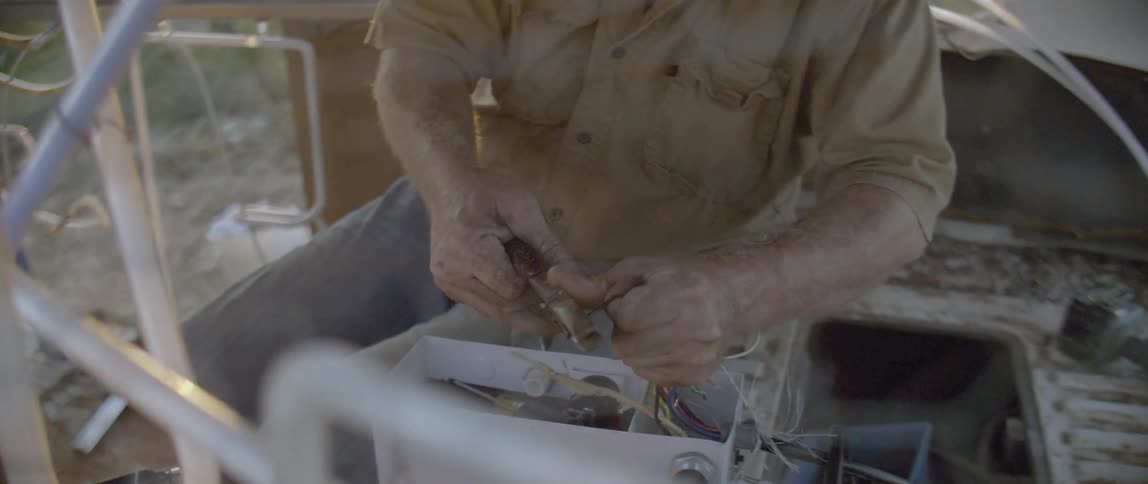 A man is cutting wires with pliers