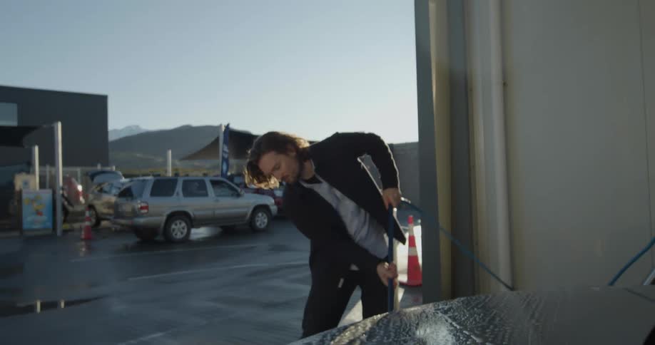 A man concentrates on pressure washing his car at a selfservice car wash