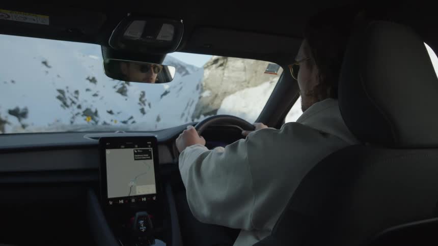 A man drives a car on a mountain road with his route displayed on a dashboard gps screen