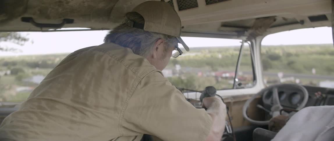 A man uses a power drill to attach a metal rod