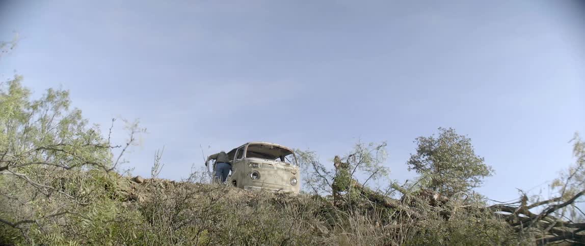 A man puts items in an abandoned van on the hill