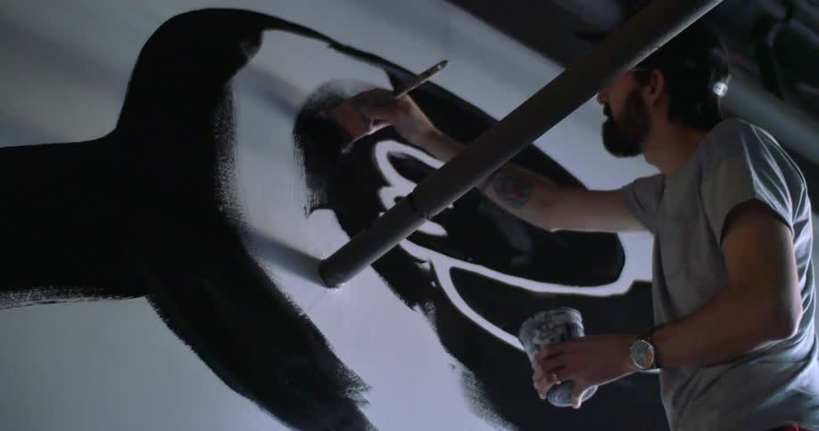 A man is painting a picture with black paint