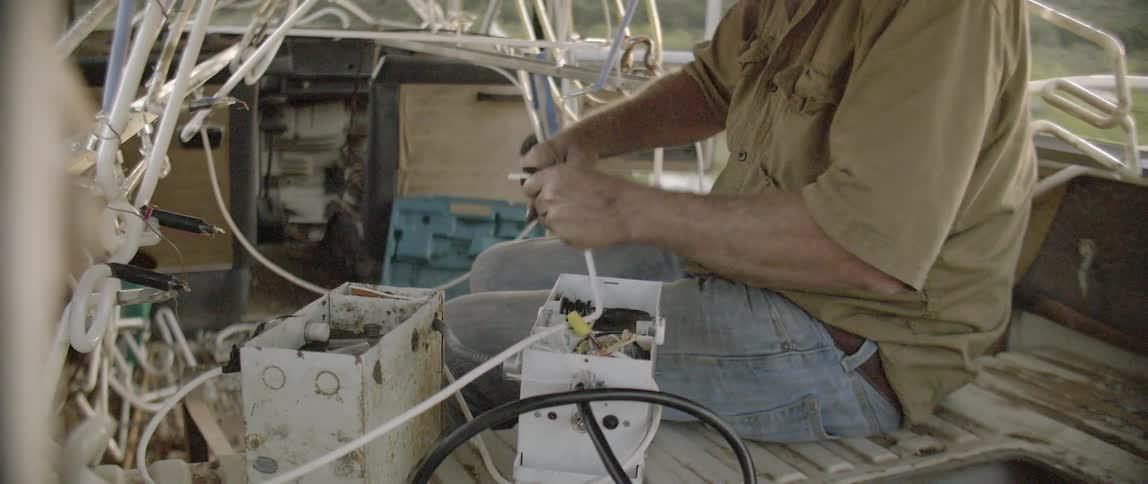 A man uses a tool to trim some plastic tubing