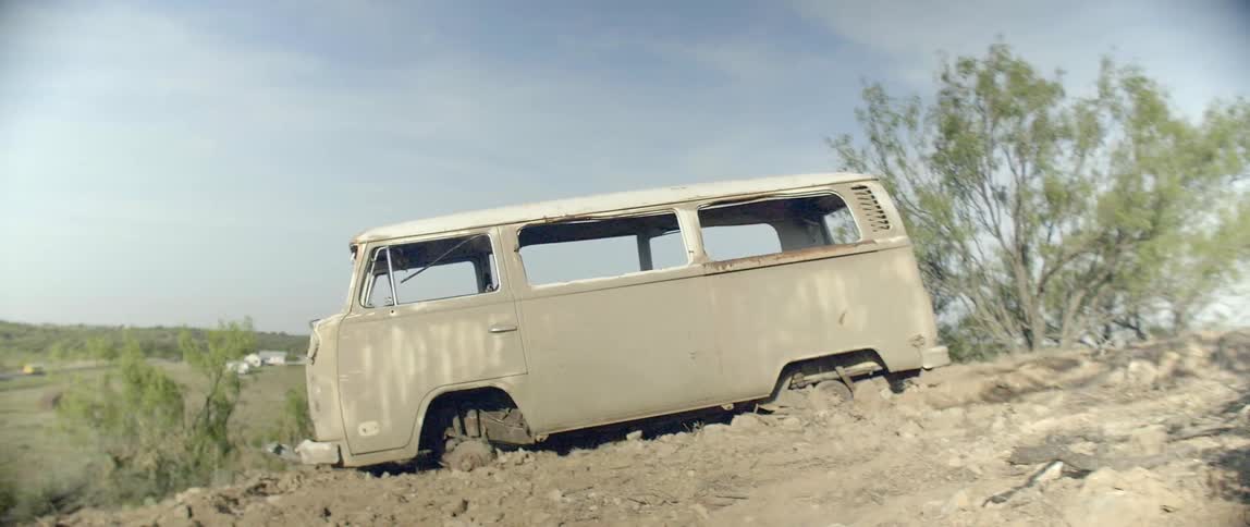 An abandoned van sits on a hillside