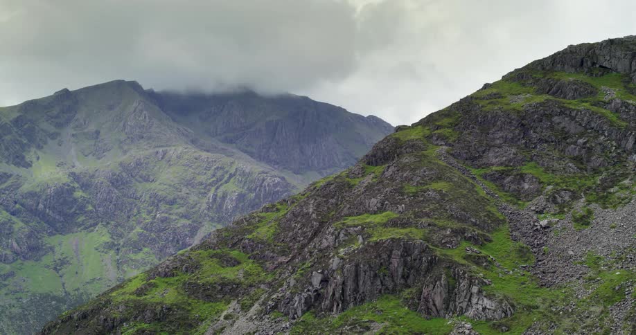 Thick clouds cover the peak of a mountain ridge behind a rocky slope