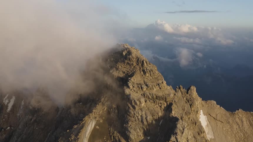 Dense clouds obscure the peak of a snow capped mountain