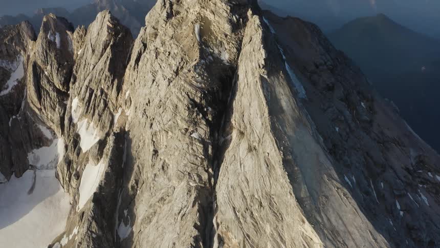 Snow settles in the cracks and ridges of a mountain top