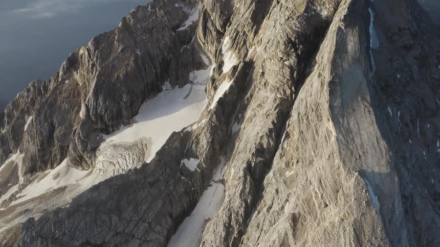 Snow settles between ridges on the side of a mountain