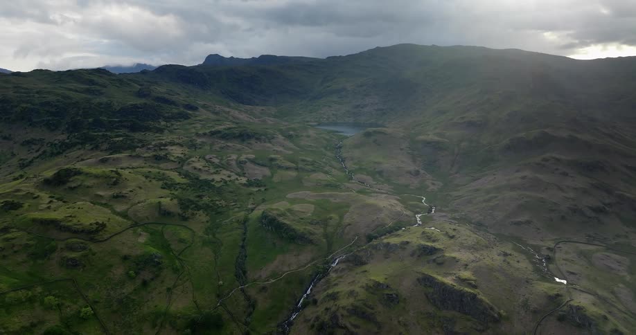Aerial view of a river flowing through he small hills on a mountain range
