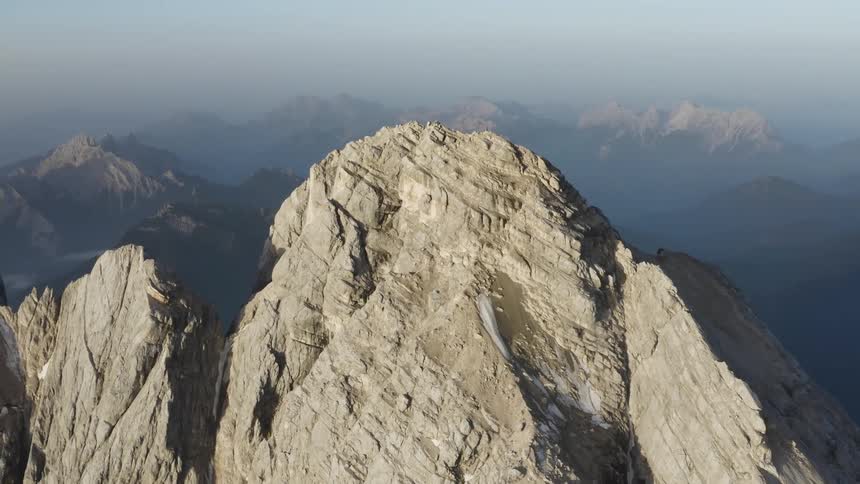 A stone mountain ridge looms over a mountain range shrouded in fog