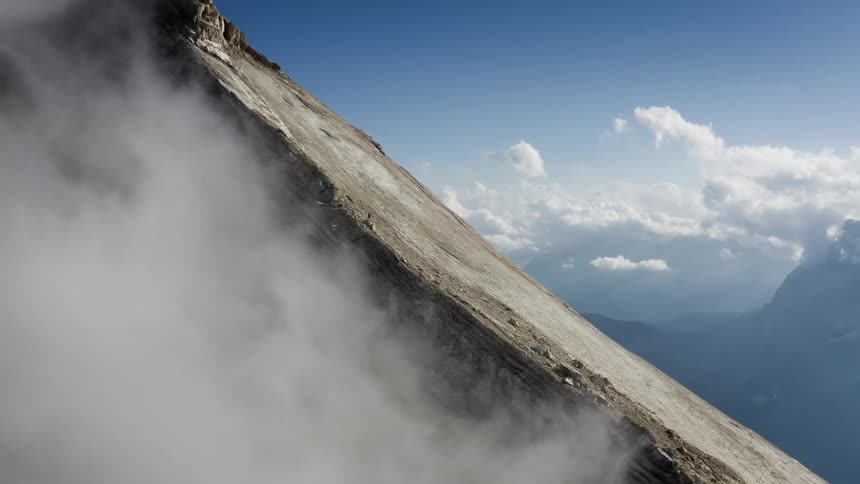 Clouds moving across the top of a cliff