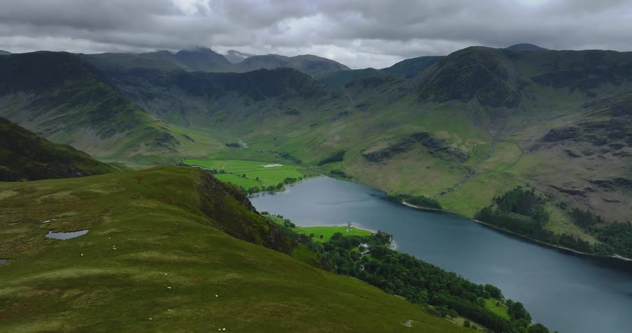 A lake on the floor of a mountain valley covered in low vegetation on a cloudy day