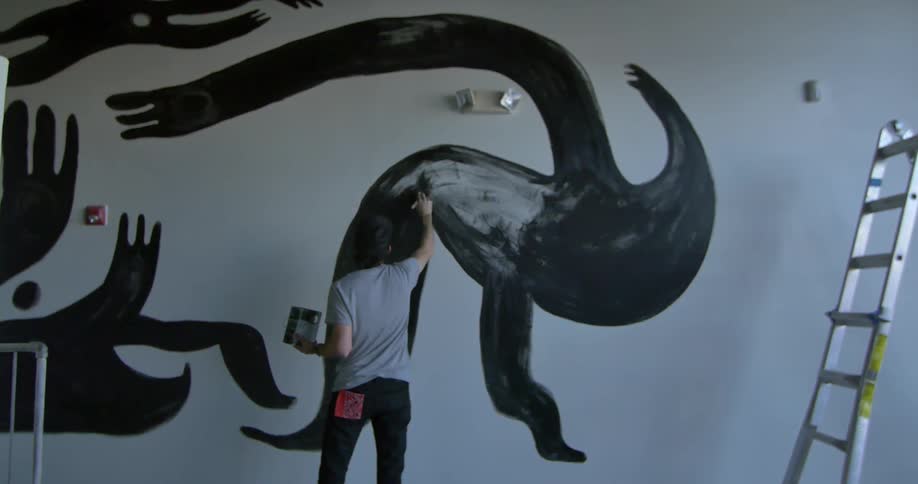 Man paints a mural on a wall