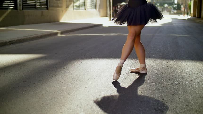 A woman is ballet dancing on a sunny day