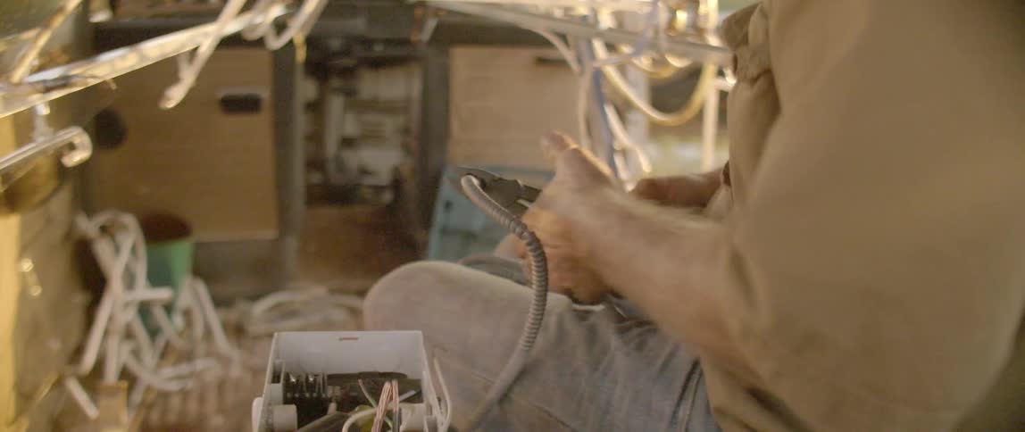 A man is sitting using pliers