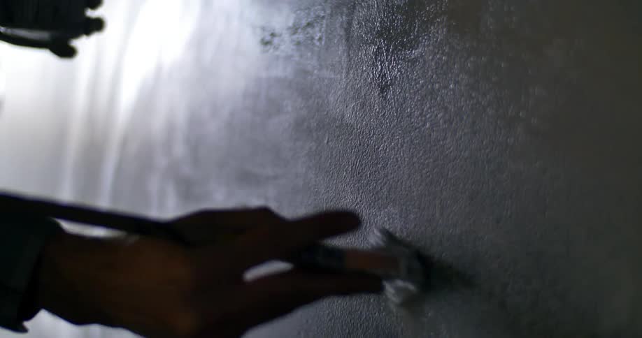 A man spreading black paint on a wall
