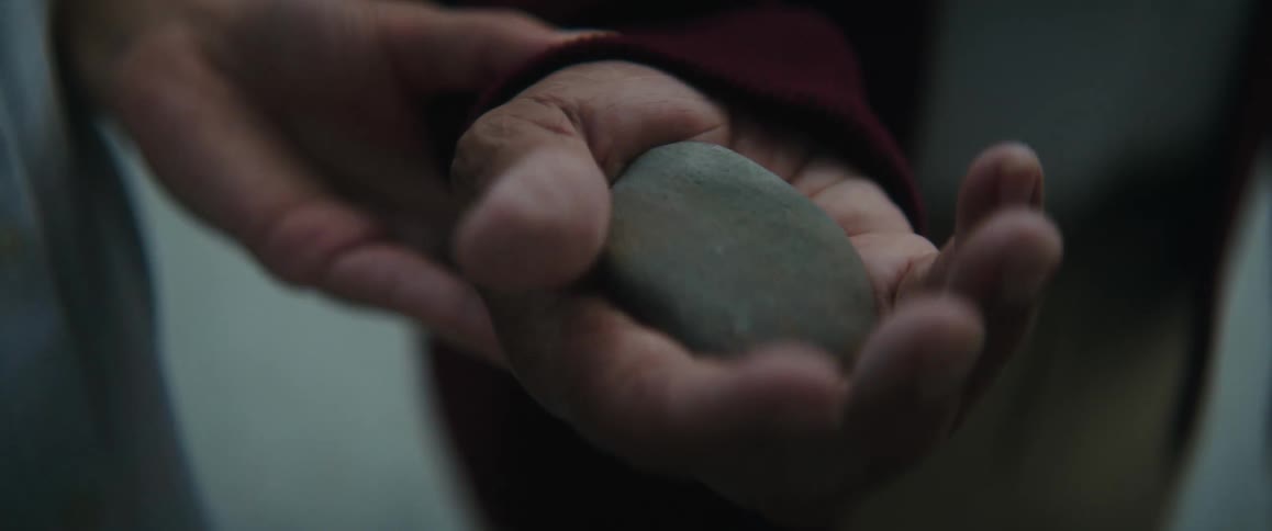 Man grasps and feels pebble placed in his hand by woman