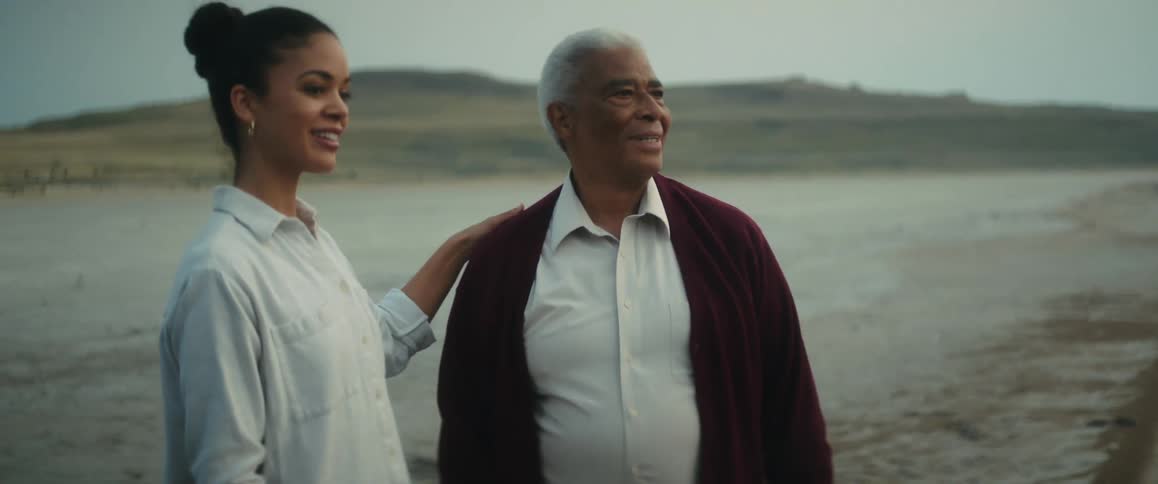 Father and daughter standing on the beach next to the ocean looking a the horizon