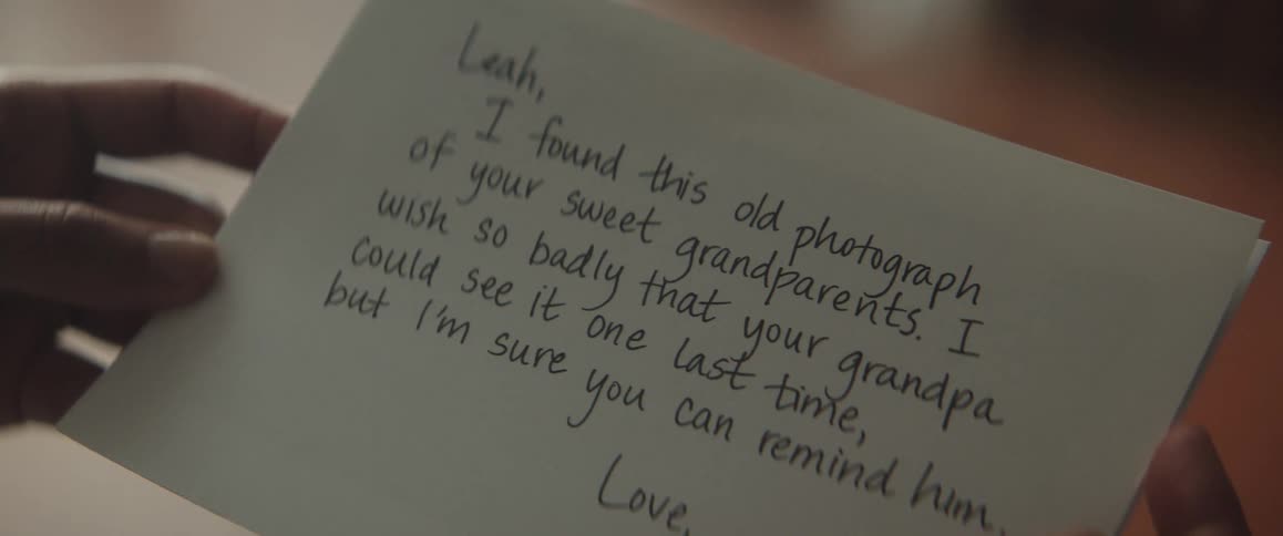 A womans hands holding a note with a photograph of her grandparents when they were young