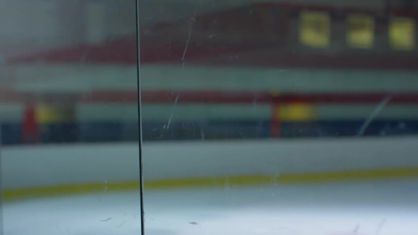 Close up of the safety glass surrounding an indoors ice hockey rink