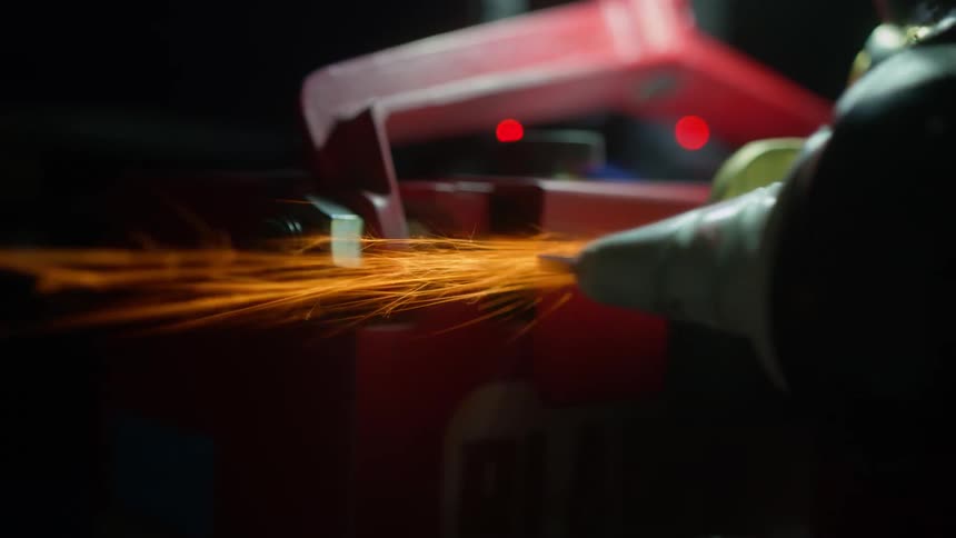 Close up of a power tool cutting a piece of machinery inside a dimly lit room