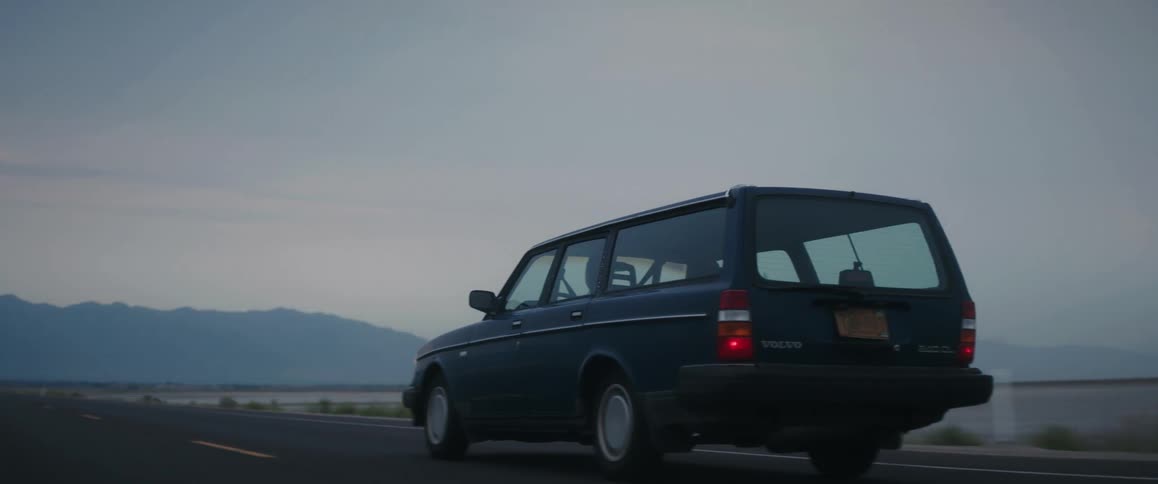 Old volvo wagon driving on a road through the desert at morning