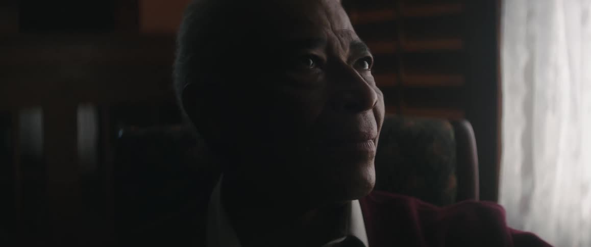 A man sitting at home near a window smiling and talking