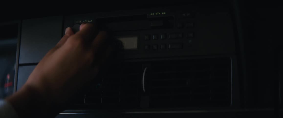 Hand reaching for the volume knob on a car stereo turning it slightly