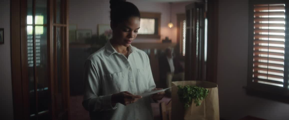 Young woman standing on the living room at home reads a letter