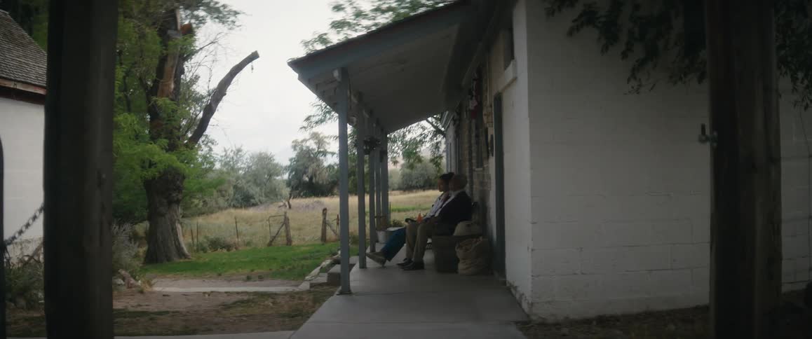 Father and daughter drink soda while sitting on the porch of a house in the countryside