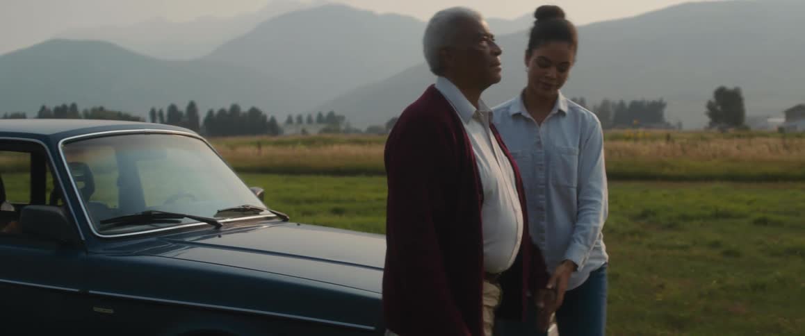 An elderly man walks and a young woman gets out of the drivers door and takes his hand as they walk away together