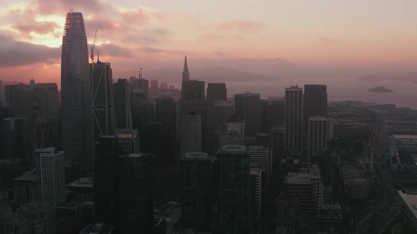 Aerial view of the silhouette of a waterfront city skyline at sunset