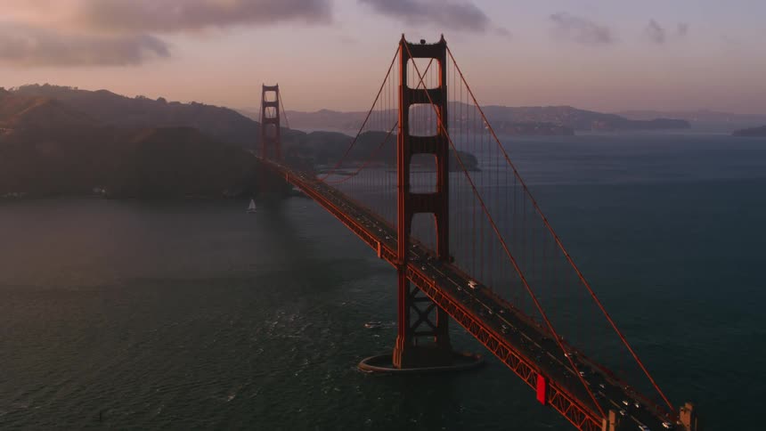 Boats travel under and around while traffic drives across the golden gate bridge