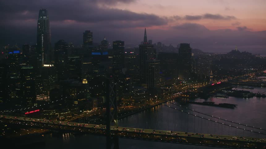Aerial view of the silhouette of a waterfront city skyline at sunset