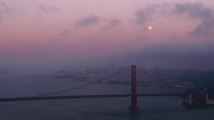 An aerial view of a full moon over water and a bridge