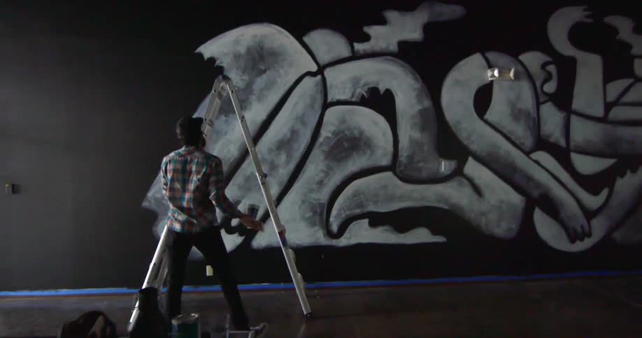 A man gets off a ladder and drags it over