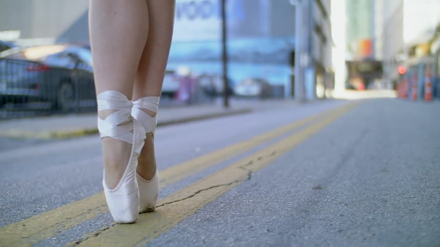 A woman is on her tiptoes in the street