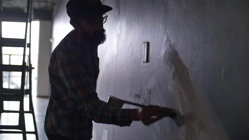 A man is painting a wall near a ladder