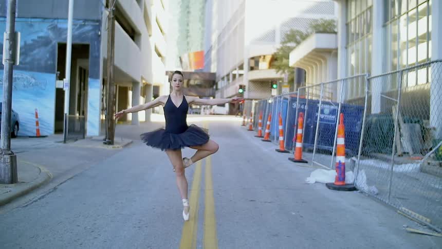 A woman ballet dances in the city