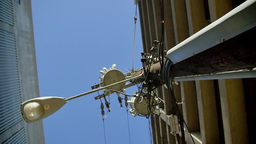 A light pole has electrical wires coming from the top