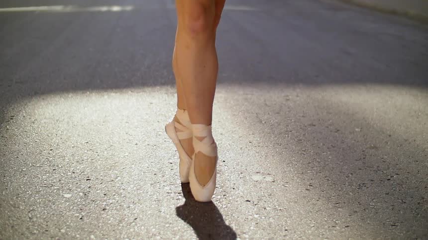 A woman is ballet dancing on the street