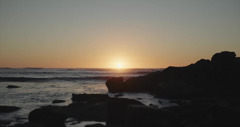 Ocean waves rolling in to the shore as the sun sets